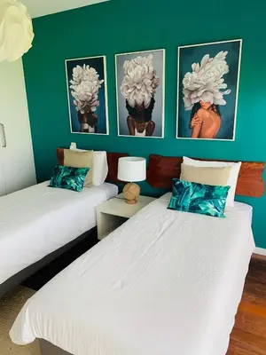two beds in a room with green walls at Villa Mar Garajau in Caniço