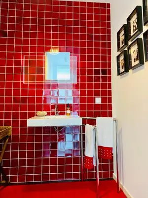 a red tiled bathroom with a sink and a mirror at Villa Mar Garajau in Caniço