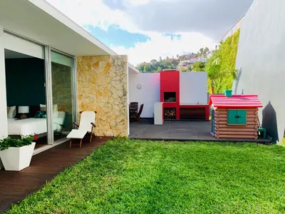 a backyard with a small house and a yard with a dog house at Villa Mar Garajau in Caniço