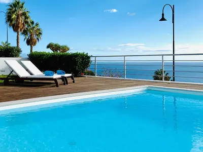 a swimming pool with chairs and a view of the ocean at Villa Mar Garajau in Caniço