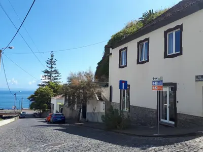 a building on the side of a street next to the ocean at Souza Beach Apartment - Porto da Cruz - Studio & Suite in Porto da Cruz