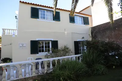 a white house with black shutters and a porch at Casa do Quintalão in Raposeira