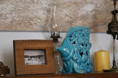 a picture and a blue vase on a table with a candle at Casa do Quintalão in Raposeira