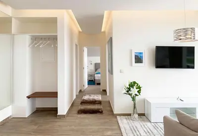a living room with white walls and a tv on the wall at Holiday Apartment Ocean View in Ribeira Brava