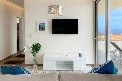 a living room with a couch and a tv at Holiday Apartment Ocean View in Ribeira Brava