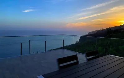 a balcony with a view of the ocean at sunset at Holiday Apartment Ocean View in Ribeira Brava