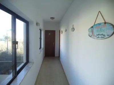 a hallway with a door and a floor to ceiling window at Quartos Maria Clara in Sagres