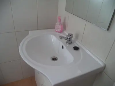 a white bathroom sink with a bottle of soap on it at Quartos Maria Clara in Sagres