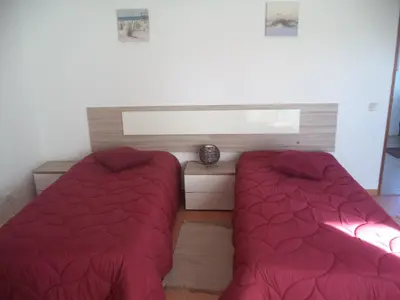 two beds in a bedroom with red comforter at Quartos Maria Clara in Sagres