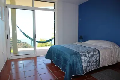 a blue bedroom with a bed and a large window at Apartamento MAR AZUL in Calheta