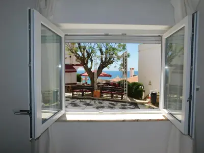a bedroom with a window with a view of a tree at Luz Beach Center in Luz