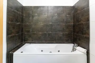 a bath tub in a bathroom with a tile wall at Casa Mia, a Dream Spot With Heated Pool in Arco da Calheta