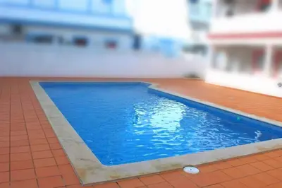 a blue swimming pool on a building with a tile floor at Amarguinha in Burgau
