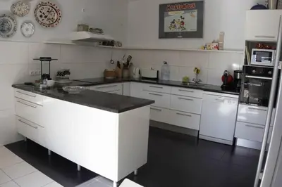 a kitchen with white cabinets and a black counter top at Raposeira de São João, the feeling of peace, space and quiet, Whole villa is yours in Fajã da Ovelha