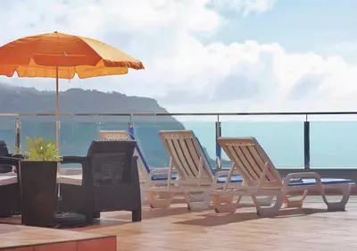 a table and chairs with an umbrella on a balcony at Madeira Island Villa Oceane Ribeira Brava in Ribeira Brava