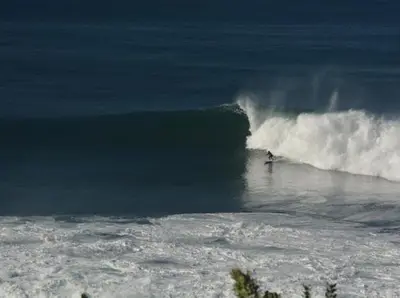 a person riding a wave on a surfboard in the ocean at CASA DO MAR in Jardim do Mar