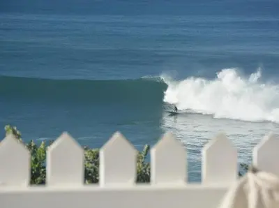 a white fence with a surfer in the ocean at CASA DO MAR in Jardim do Mar