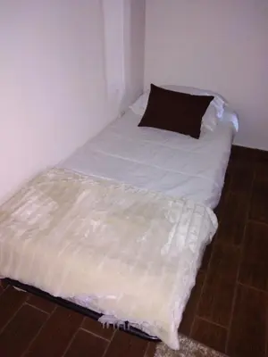 a bed in a corner of a room with a pillow at Casa dos Valentes in Santo Espírito