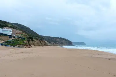 a sandy beach with a house and the ocean at Muramaris in Salema