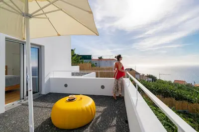a woman standing on a balcony looking out at the ocean at Casas da Vargem shared swimming pool by An Island Apart in Ponta do Sol