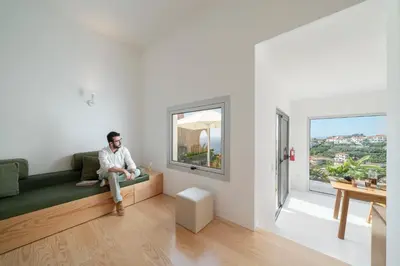 a man sitting on a couch in a room with a window at Casas da Vargem shared swimming pool by An Island Apart in Ponta do Sol