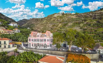 a large white building in front of a mountain at 1905 Zino's Palace in Ponta do Sol