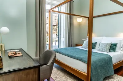 a hotel room with a bed and a chair and a desk at 1905 Zino's Palace in Ponta do Sol