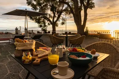 a table with food and drinks on it with the sunset at 1905 Zino's Palace in Ponta do Sol