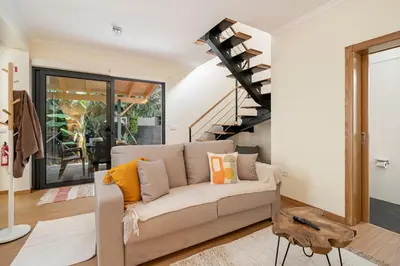 a living room with a couch and a spiral staircase at Oscar's House by An Island Apart in Ponta do Sol