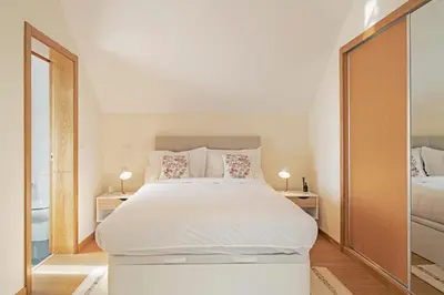 a bedroom with a large white bed and two lamps at Oscar's House by An Island Apart in Ponta do Sol