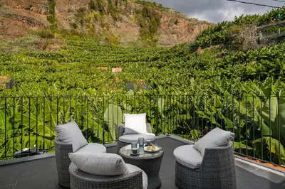 a patio with wicker chairs and a table on a balcony at Oscar's House by An Island Apart in Ponta do Sol