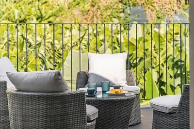 a patio with wicker chairs and a table with a plate of food at Oscar's House by An Island Apart in Ponta do Sol