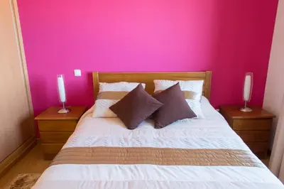 a bedroom with a pink wall and a bed with two candles at “VENIK HOUSE” sea_mountains_relaxing_barbecue in Funchal
