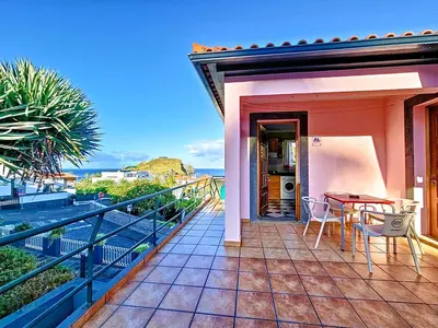a balcony of a house with a table and chairs at Domus Dino in Porto da Cruz
