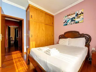 a bedroom with a white bed with a wooden headboard at Domus Dino in Porto da Cruz