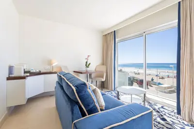 a living room with a blue couch and a view of the ocean at Residence Sol e Mar in Salema