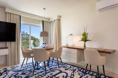 a living room with a table and chairs and a television at Residence Sol e Mar in Salema