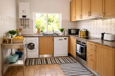 a kitchen with wooden cabinets and a washer and dryer at Casadaluz 86 - Porto dona Maria casa do mar , 2 bedrooms , Amazing sea view , salt water pool , wifi in Luz