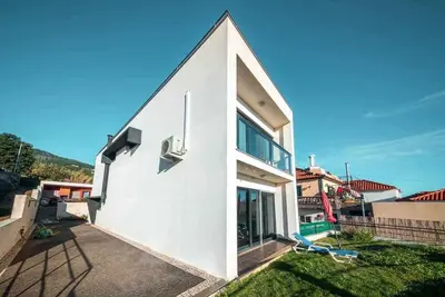 a white house with a large window on the side of it at Casa da Terça - Nice View and Parking in Funchal