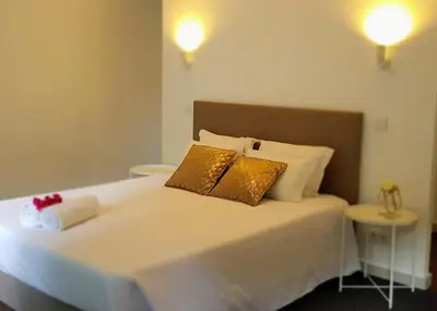 a white bed with two gold pillows on it at CBA Suites Madeira in Funchal