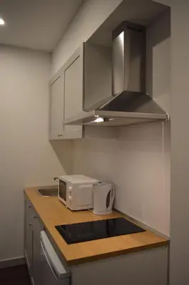 a small kitchen with a microwave and a sink at CBA Suites Madeira in Funchal