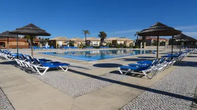 a swimming pool with blue chairs and umbrellas at LakeView Boavista in Lagos