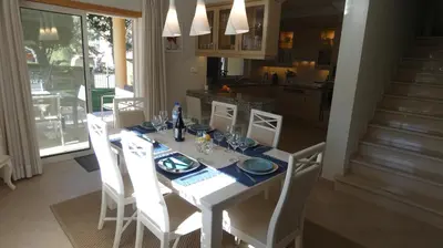 a dining room table with white chairs and a kitchen at LakeView Boavista in Lagos