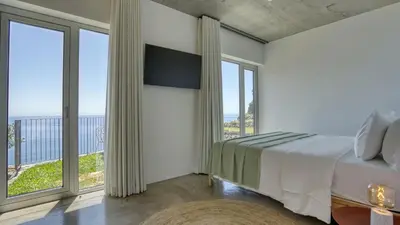 a bedroom with a bed and a tv and windows at Socalco Nature Calheta in Calheta