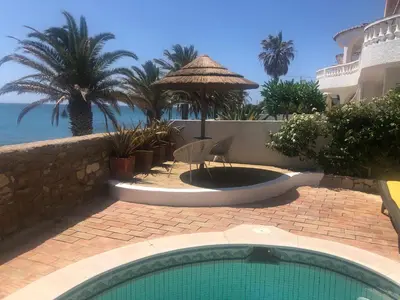 a swimming pool in front of a resort with the ocean at Beach front/waterside apartment in Luz