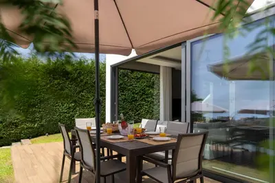 a table with chairs and an umbrella on a patio at OurMadeira - Bella Vita in Calheta