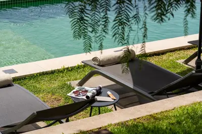 a picnic table and chairs next to a swimming pool at OurMadeira - Bella Vita in Calheta