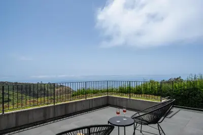a balcony with two chairs and a table with wine glasses at OurMadeira - Bella Vita in Calheta