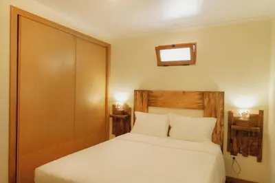 a bedroom with a white bed with a wooden headboard at Casa Maria Quinta 4 