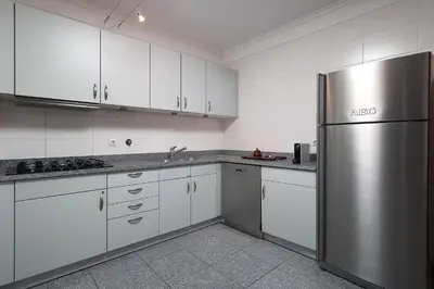 a kitchen with white cabinets and a stainless steel refrigerator at Vista Monumental by LovelyStay in Funchal